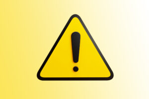 na żółtym tle trójkątny znak uwaga